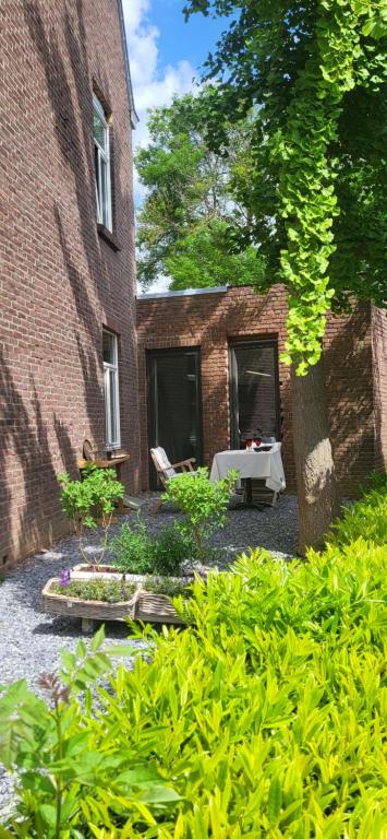 een bakstenen gebouw met een tafel in een tuin bij Mijn appartement met sauna en lift in Voerendaal