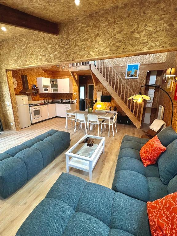 un salon avec un canapé bleu et une table dans l'établissement Chalet Bois Baobab 5 min à pieds de l'océan, à Montalivet-les-Bains