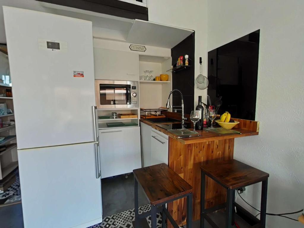 Il comprend une cuisine équipée d'un réfrigérateur blanc et d'un comptoir en bois. dans l'établissement Appart Studio Mezzanine 2 couchages PORT LEUCATE NATURISME PL010-654, à Leucate-Plage