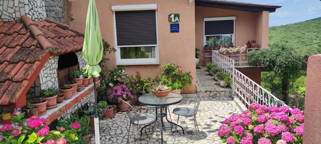 un patio con tavolo e fiori di fronte a una casa di Rajski vrt a Crikvenica