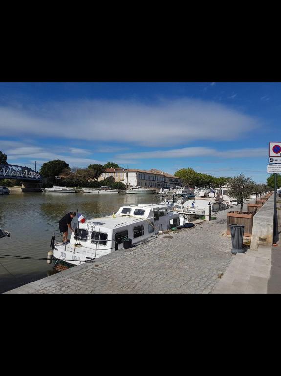 un homme monte sur un bateau dans une marina dans l'établissement Appartement centre historique, à Beaucaire