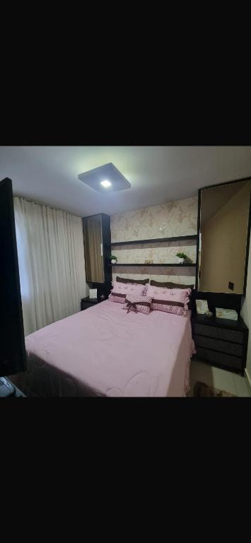 a bedroom with a large bed with pink sheets at Apartamento mobiliado in Goianésia