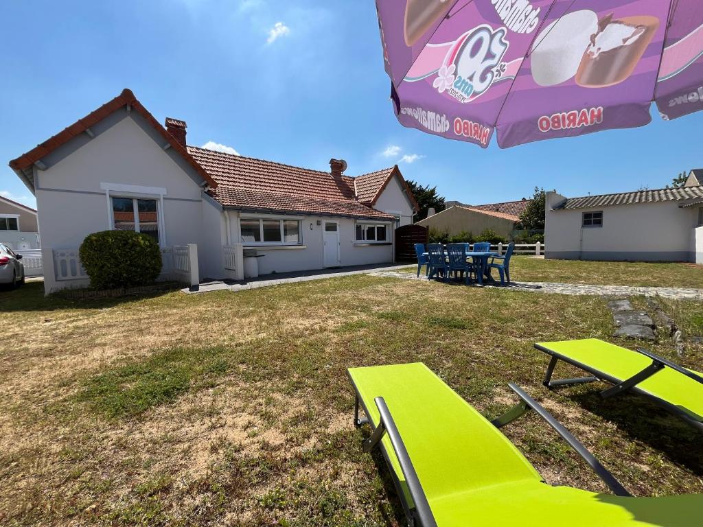 une cour avec une chaise verte et un parasol dans l'établissement Maison de famille à 300m de la plage, à Saint-Jean-de-Monts