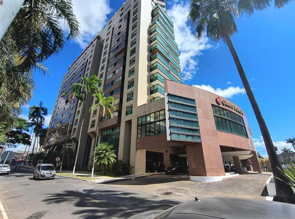 巴西利亚Flat particular no Hotel Grand Mercure com varanda, garagem e wi-fi的一条街道前方有棕榈树的高楼
