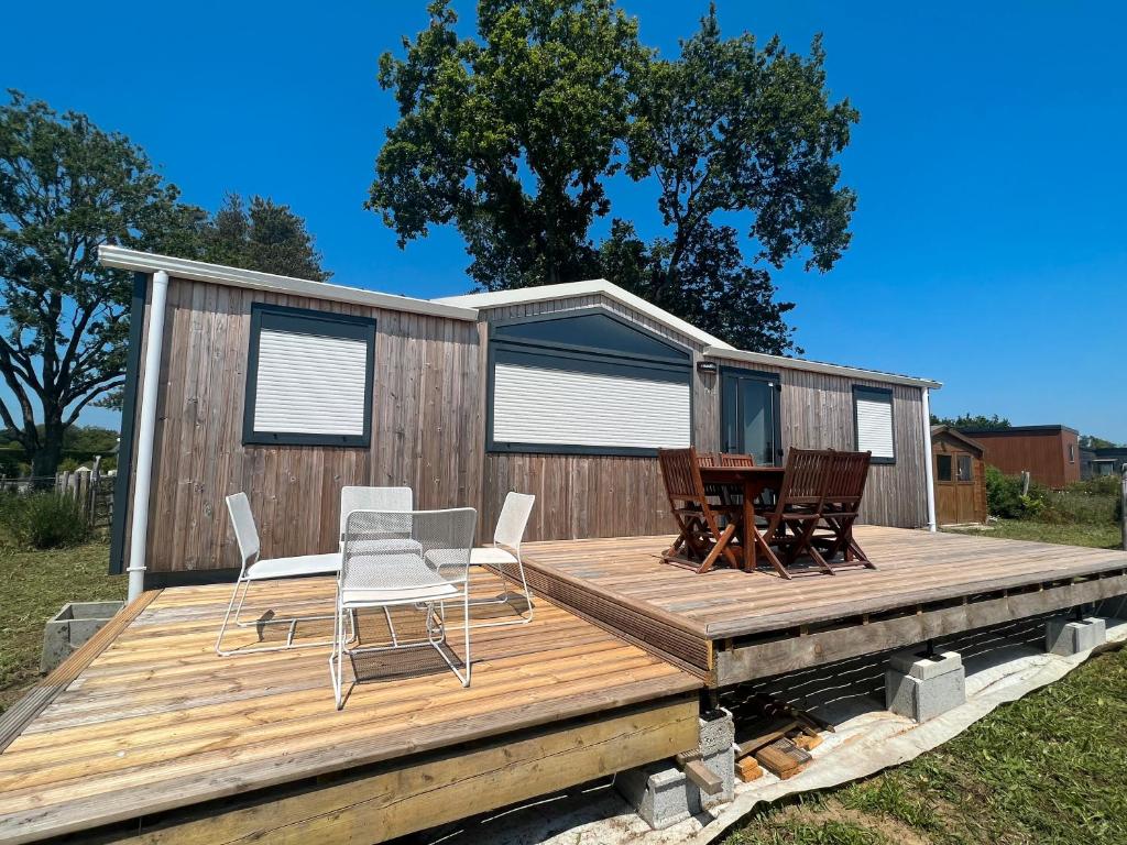 une maison dotée d'une terrasse avec des chaises et une table dans l'établissement Mobil home 4 saisons Saint-Jacques, à Sarzeau