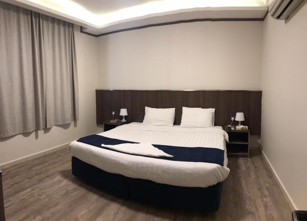 a bedroom with a large bed with two nightstands and two lamps at Hayat Al madinah Hotel فندق حياة المدينة in Al Madinah