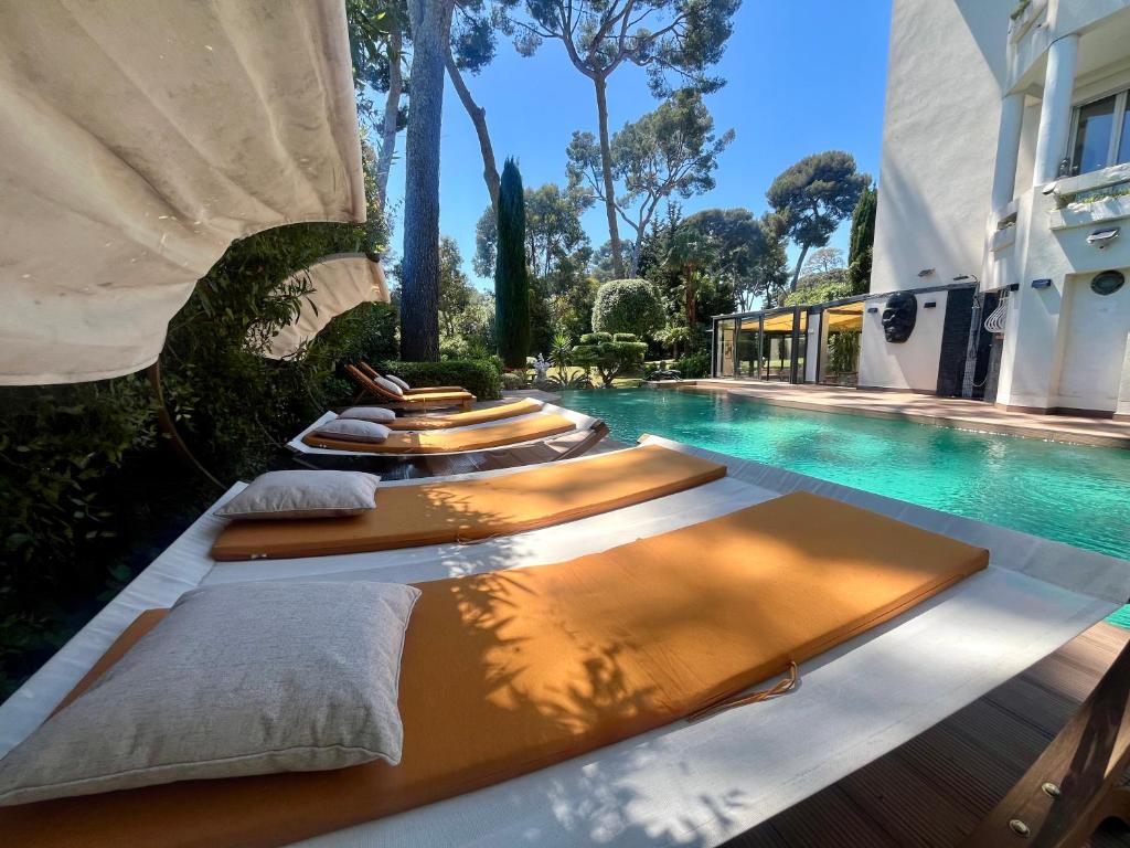 une piscine avec trois chaises longues à côté d'un bâtiment dans l'établissement Un Joyau vue Mer Cap d'Antibes Piscine Body Fitness Sauna & Plage, à Antibes
