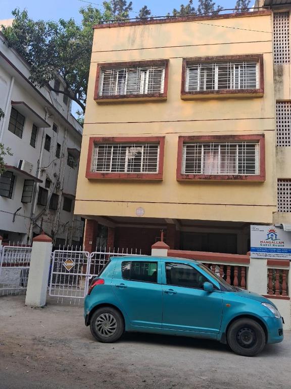 a blue car parked in front of a building at Mangallam Guest House in Pune