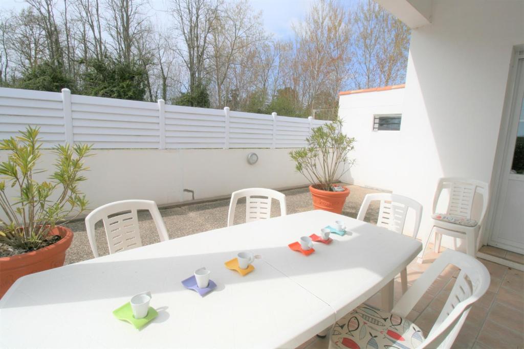 une table blanche et des chaises sur une terrasse dans l'établissement Agréable maison, aperçu mer, wifi, à La Tranche-sur-Mer