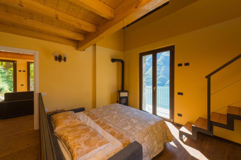 een slaapkamer met een bed en een groot raam bij Tra Lago e Montagna Baita la Morena in Nesso