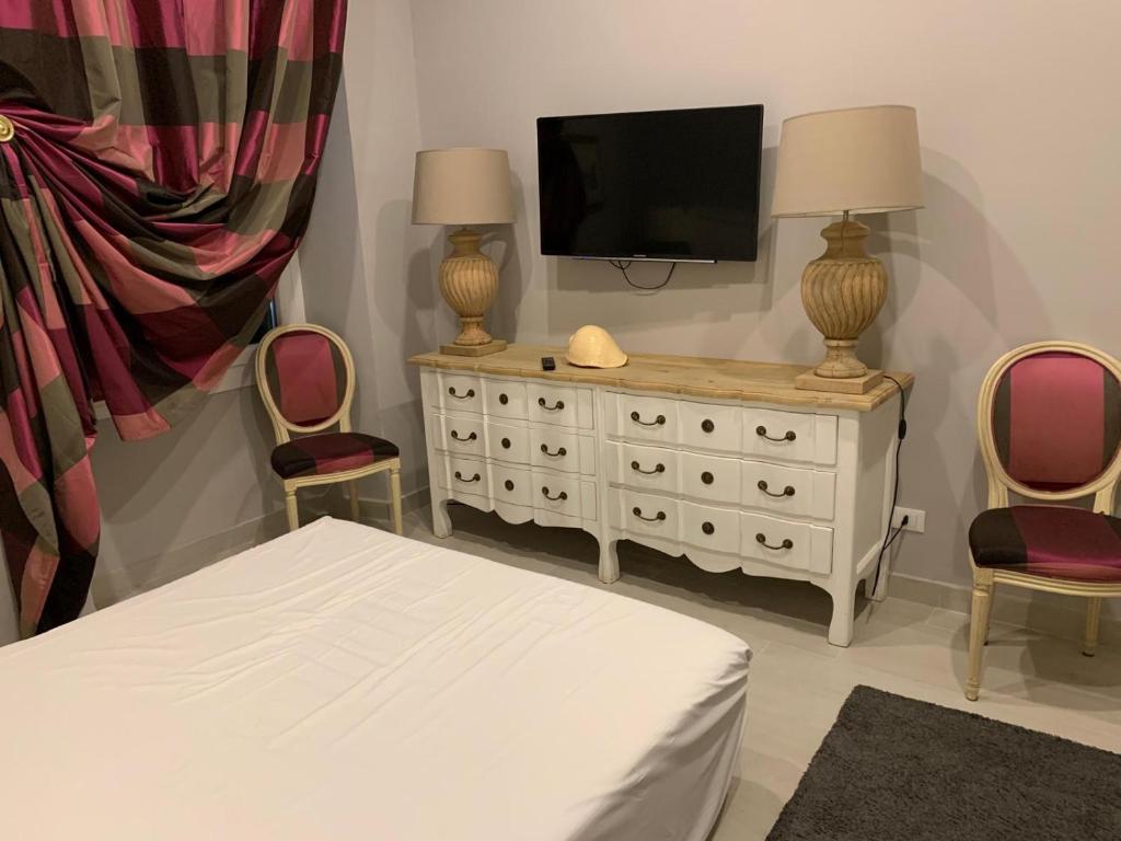 1 dormitorio con cama y vestidor con TV en Emily's Luxury Apartments, en San Remo