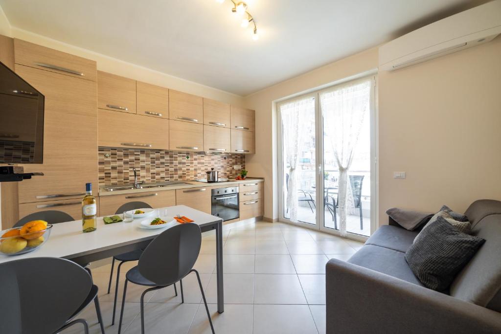Una cocina y una sala de estar con una mesa y un sofá. en Sirio - bilocale comodo a 200 m dal mare e con piscina sul tetto, en Borghetto Santo Spirito