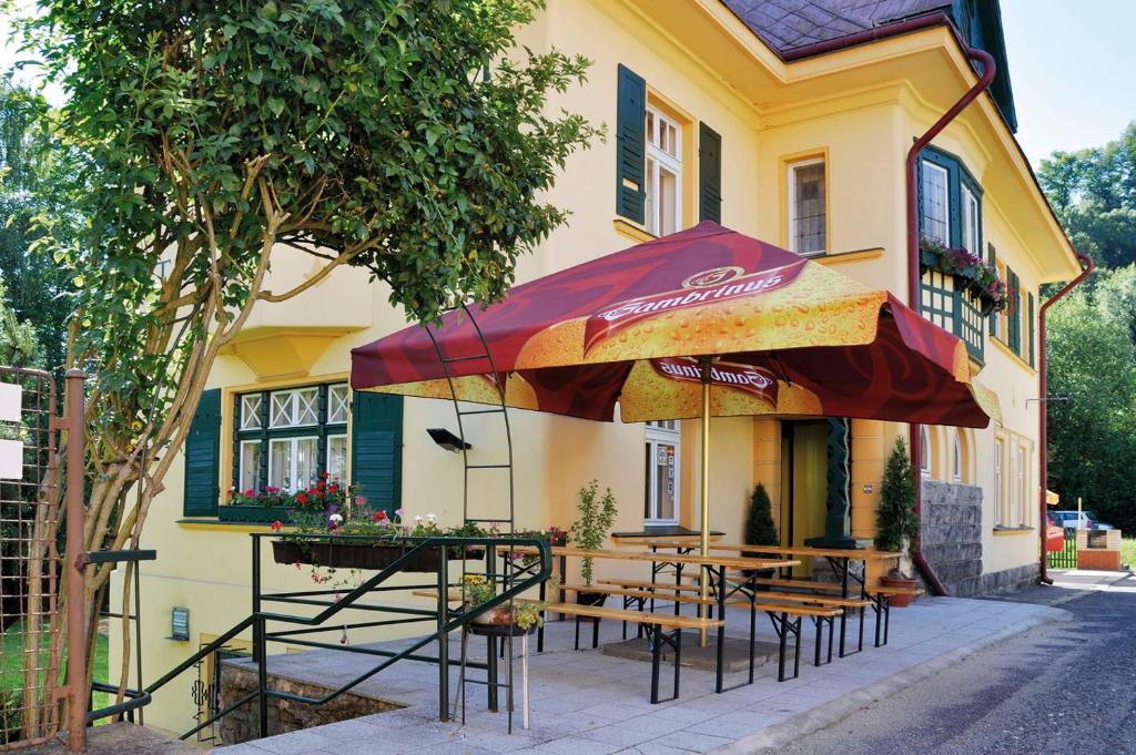 un restaurante con mesas y una sombrilla frente a un edificio en Penzion Marion, en Děčín