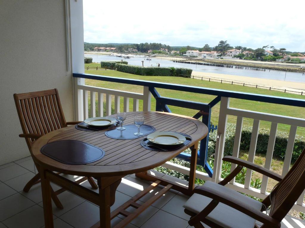 une table et des chaises sur un balcon avec vue sur l'eau dans l'établissement Les Huniers, à Mimizan