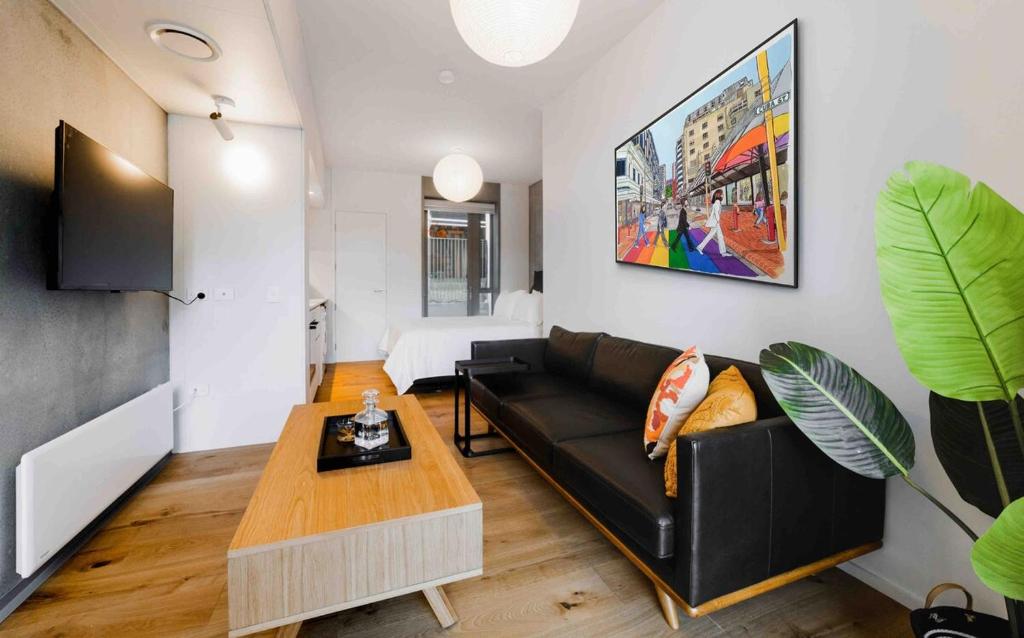 a living room with a black couch and a table at City Central Retreat - Sleek Studio Living in Wellington