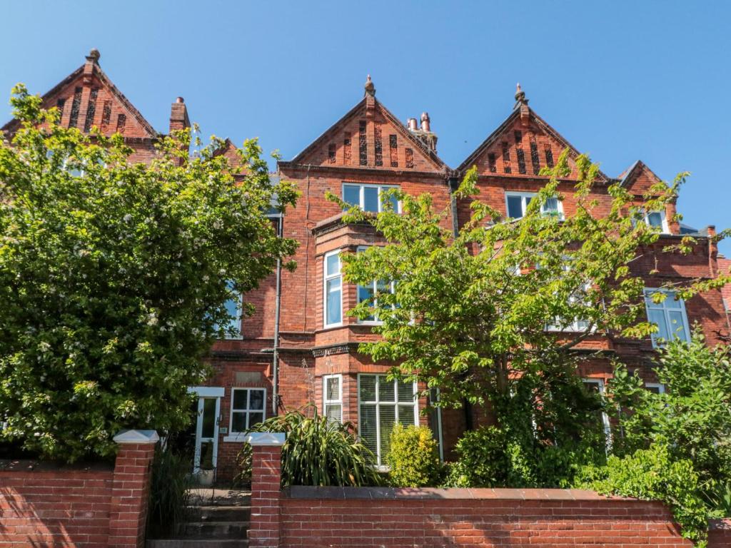 an old red brick house with trees in front of it at Royal Victoria House in Scarborough