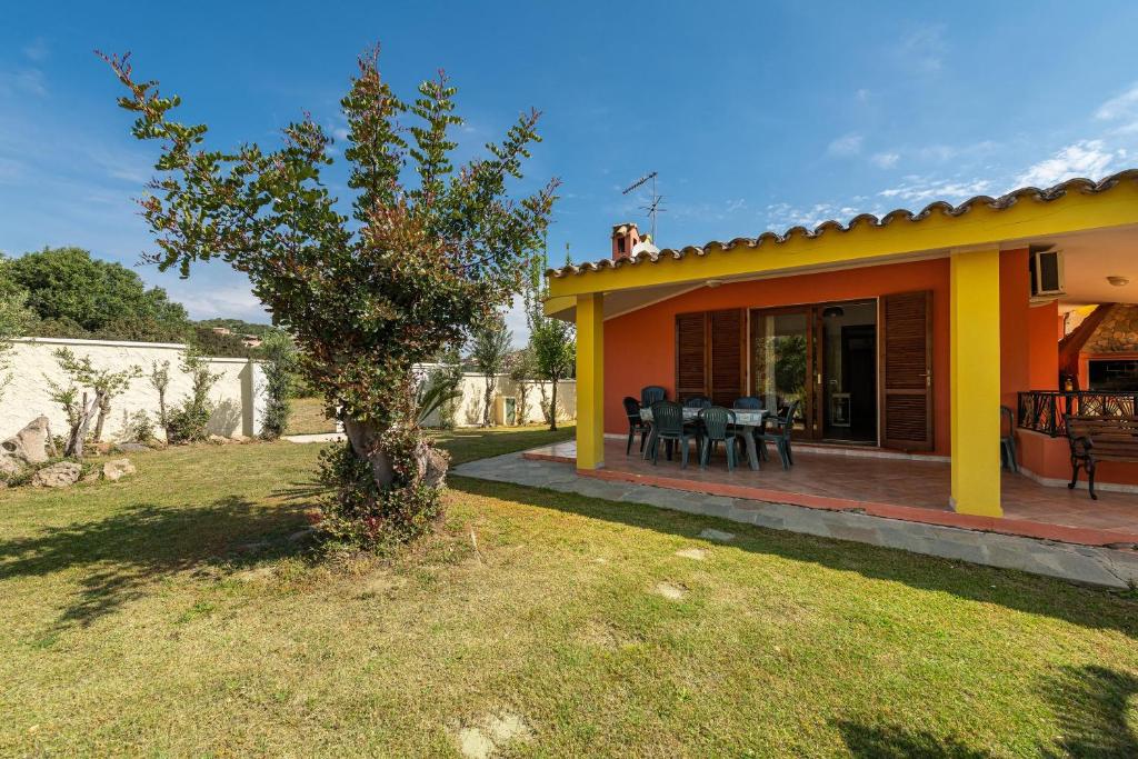 żółty dom z patio i drzewem w obiekcie Casa Nicoletta w mieście Villasimius