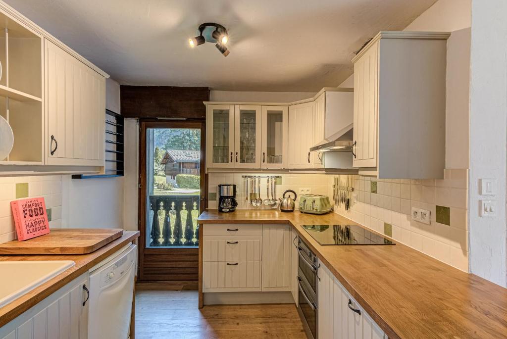 une cuisine avec des placards blancs et une grande fenêtre dans l'établissement APARTMENT CHAMOUNY - Alpes Travel - Chamonix - Sleeps 8, à Chamonix-Mont-Blanc