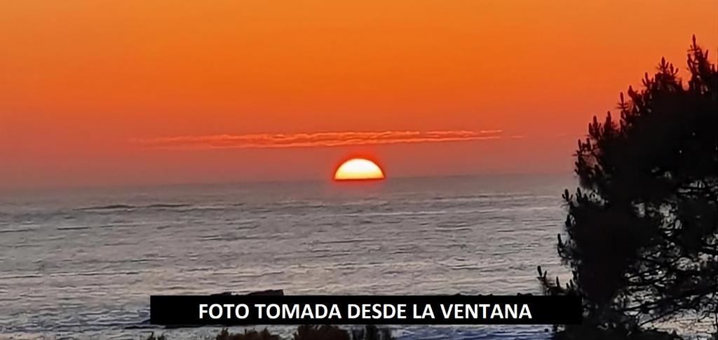 a sunset over the ocean with the sun in the horizon at Carnota PLAYA a 100 metros in Carnota