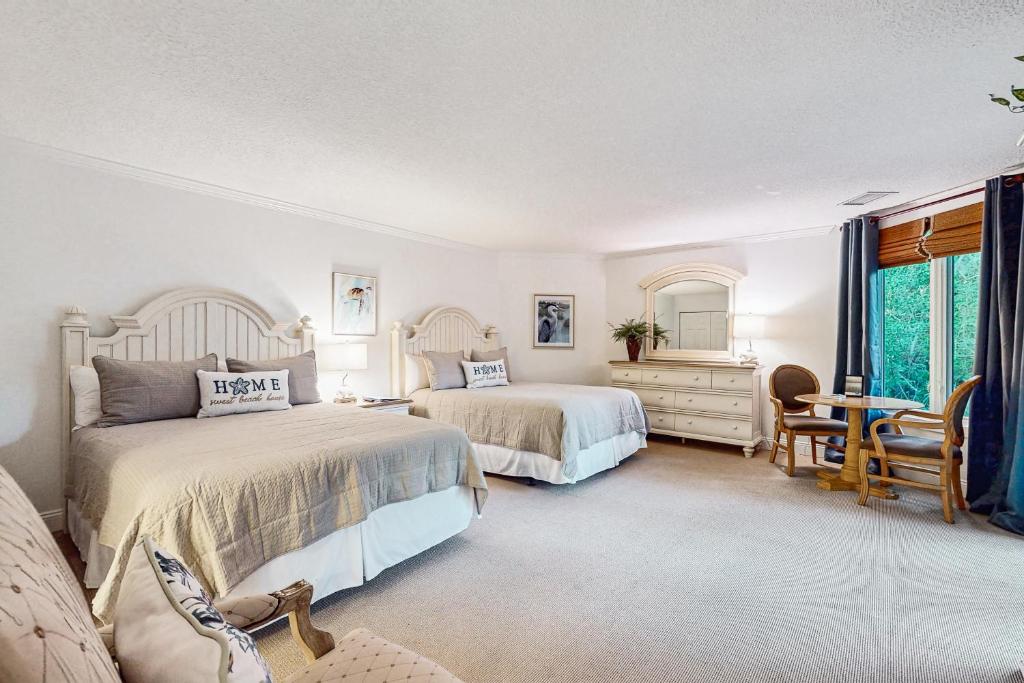 a bedroom with two beds and a table and chairs at Ameila Island Plantation condo with beach access, private patio and pool. in Fernandina Beach