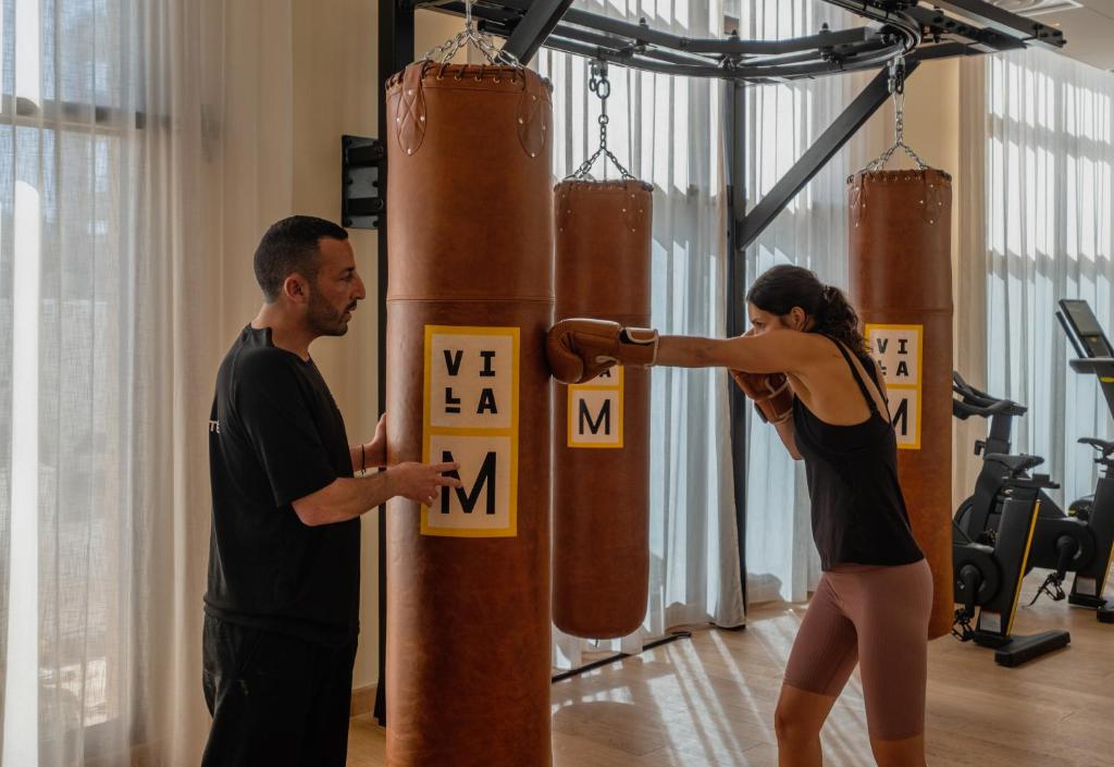 a man and a woman standing next to a punching bag in a gym at Hôtel Villa M Marseille in Marseille