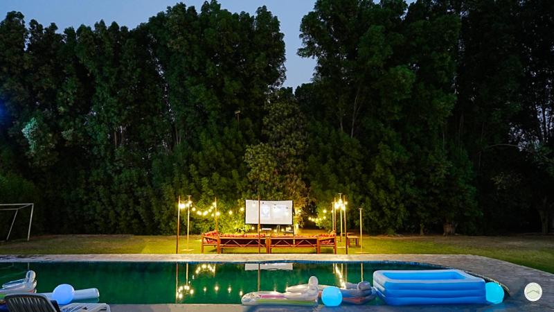 a swimming pool with a table and a screen next to it at Greenland Farm in Dubai