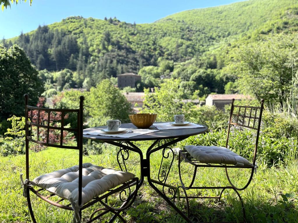 - une table avec 2 chaises et un bol dans l'établissement Le Mazet du Ron des Perles, à Valleraugue