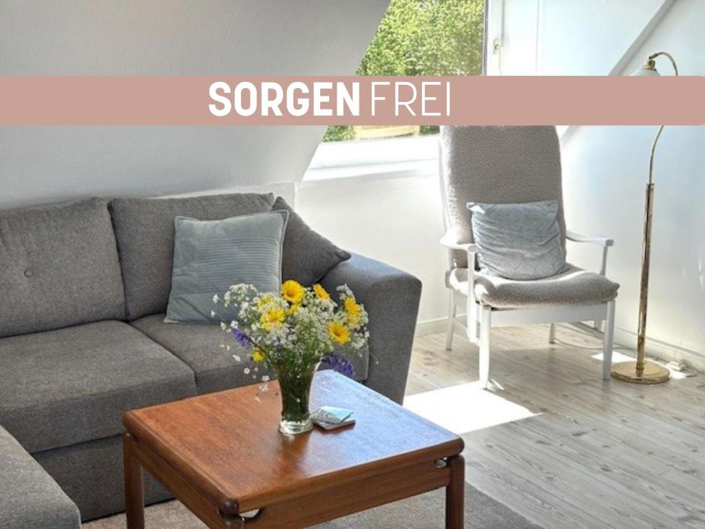a living room with a couch and a table with flowers at Sorgenfrei -Ruhe und Erholung in schöner Studiowohnung in Glücksburg