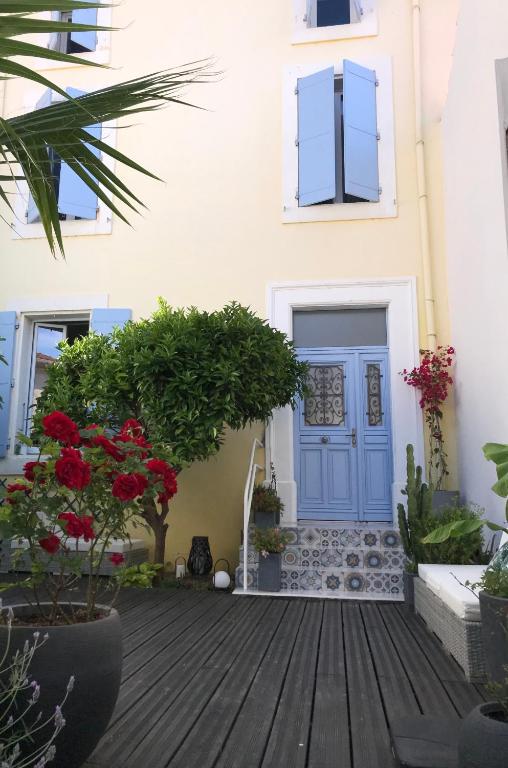 une porte bleue sur un bâtiment blanc avec des fleurs dans l'établissement Chez Emmanuel et Cristiane chambre chez l'habitant, à Ouveillan