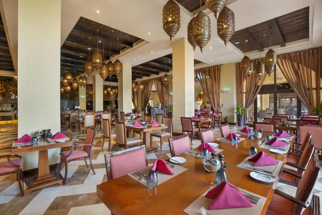 a restaurant with wooden tables and chairs and pink napkins at Aldhafra Resort, Vignette Collection by IHG in Madīnat Zāyid
