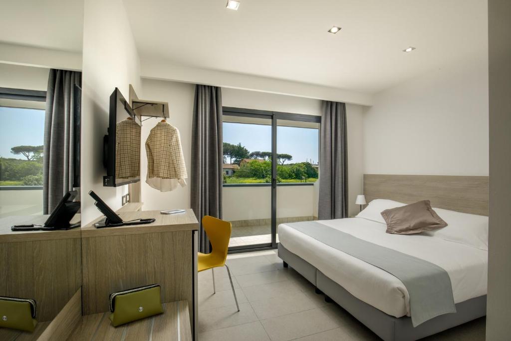Un dormitorio con una cama y un escritorio con una computadora. en Simon Hotel Aprilia, en Aprilia