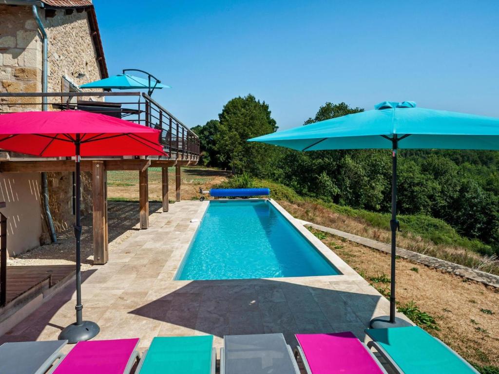 a swimming pool with two umbrellas and a swimming poolvisor at Le petit Perigord in Fouleix