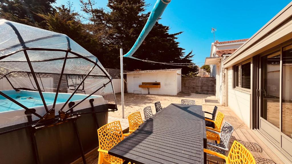 d'une terrasse avec une table, des chaises et un bateau. dans l'établissement Maison Hirondelles, piscine mer et forêt, à Saint-Jean-de-Monts