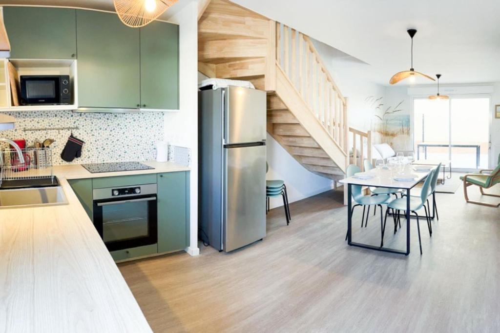 Il comprend une cuisine équipée d'un réfrigérateur et d'une table avec des chaises. dans l'établissement Charming 85 m house with terrace in Stella-Plage, à Cucq