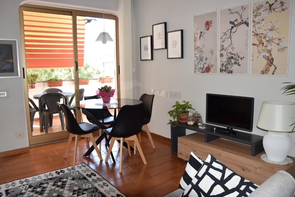 salon ze stołem, krzesłami i telewizorem w obiekcie Welcome Home w mieście Lido di Ostia