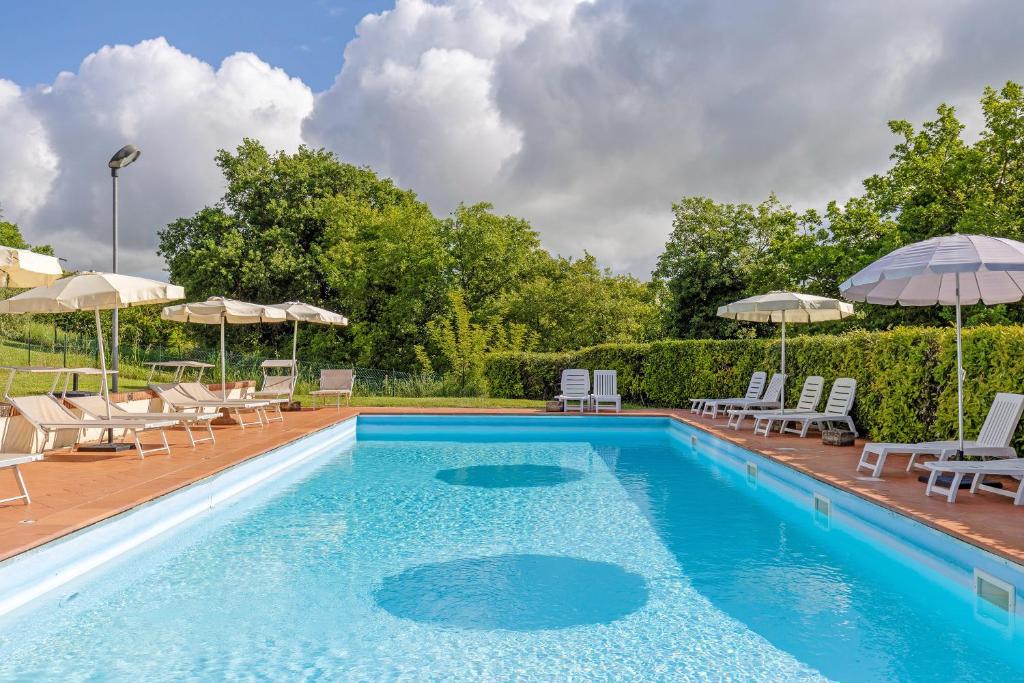 a swimming pool with lounge chairs and umbrellas at Agriturismo Le Ville in Lano