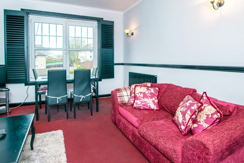 a living room with a red couch and a table at Cosy & Central 2BD Apartment Milngavie, Glasgow in Milngavie