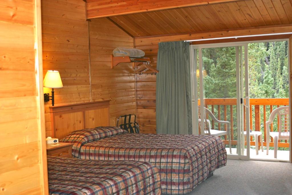 a bedroom with two beds and a balcony at Denali Grizzly Bear Resort in McKinley Park