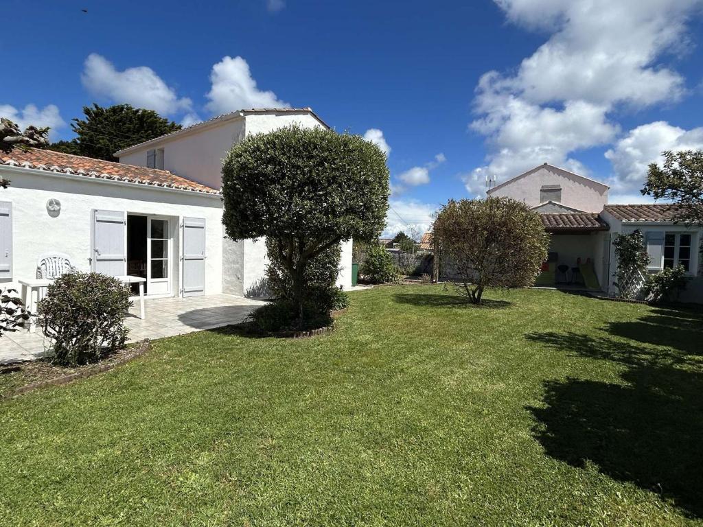 une cour d'une maison avec un arbre dans la cour dans l'établissement Maison 5 pièces avec jardin clos, terrasse, à proximité de la plage et du centre, 8 couchages - FR-1-224B-157, à Noirmoutier-en-l'lle