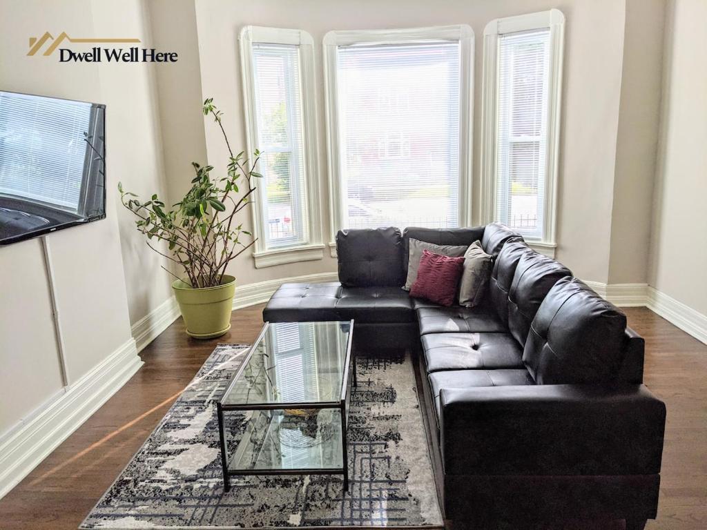 a living room with a leather couch and a glass coffee table at Spacious Bronzeville Apartment in Chicago