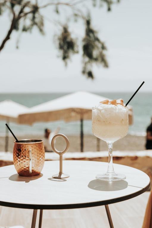 a table with a margarita and a drink on the beach at Sagredo Boutique Hotel & Spa in Ágios Fokás