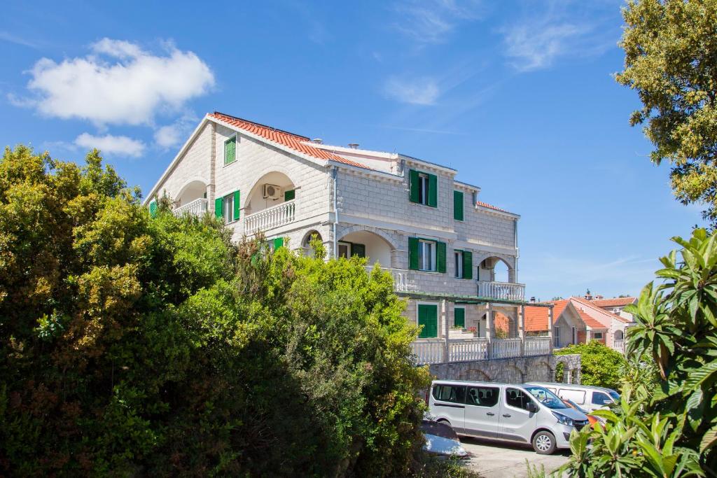 un edificio con persiane verdi e un'auto parcheggiata di fronte di Apartments Chiara a Korčula