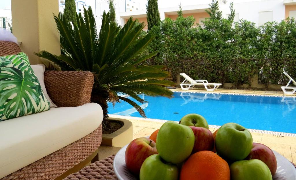 uma taça de fruta numa mesa ao lado de uma piscina em Villa Moments - Guest House em Portimão