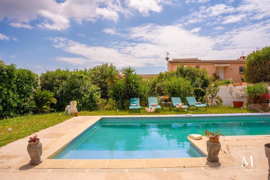 une piscine avec des chaises bleues et une maison dans l'établissement Maison avec piscine au calme à Sanary-sur-Mer, à Sanary-sur-Mer