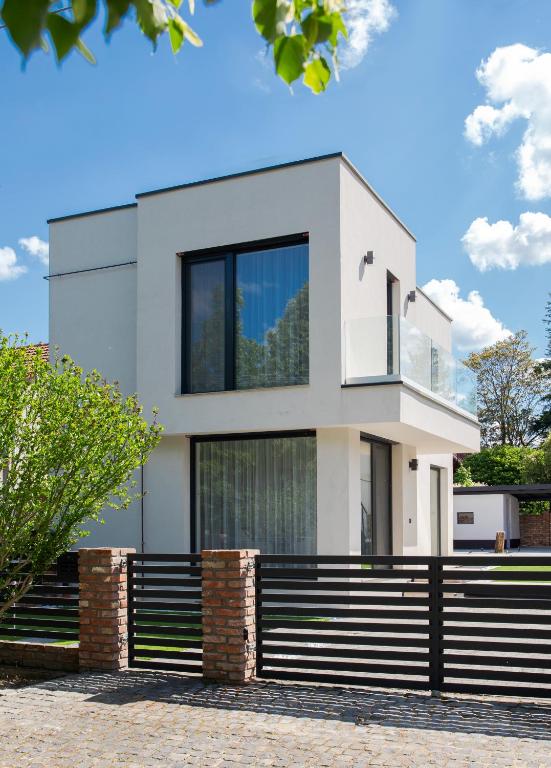 a white house with a black fence in front of it at Bovi Lux Apartman in Nyíregyháza