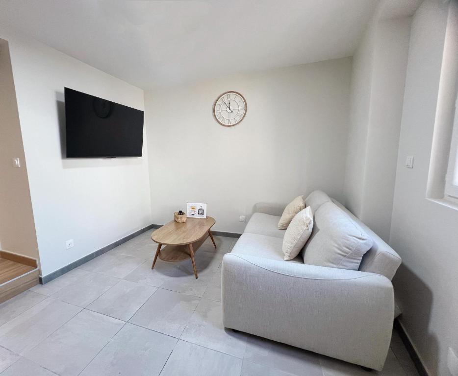 un salon avec un canapé et une horloge au mur dans l'établissement Japandi en centre-ville, à Narbonne
