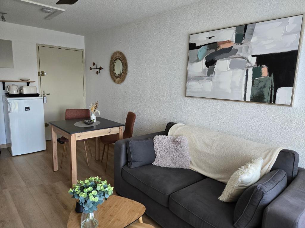 a living room with a couch and a table at Appartement paisible à 300m de la plage in Le Grau-du-Roi