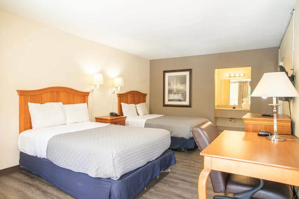 Una habitación de hotel con dos camas y un escritorio. en OYO hotel Greensboro east I 40, en Greensboro