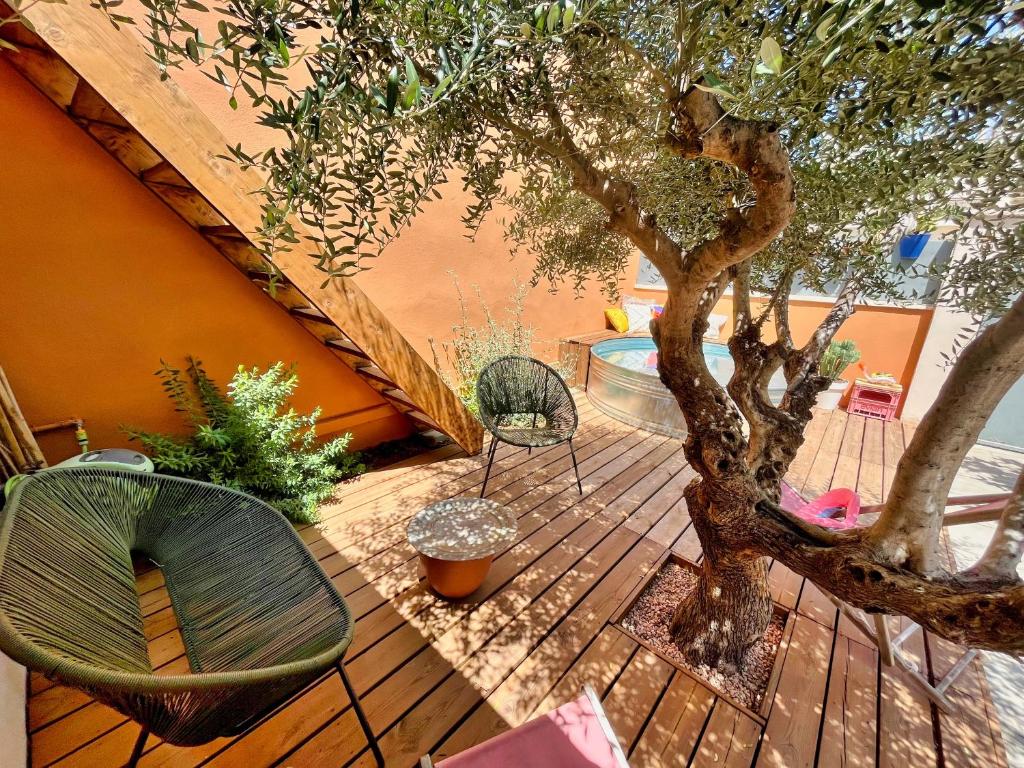 une terrasse en bois avec un arbre et un banc dans l'établissement Maison de ville familiale, bel extérieur, piscine !, à Nîmes