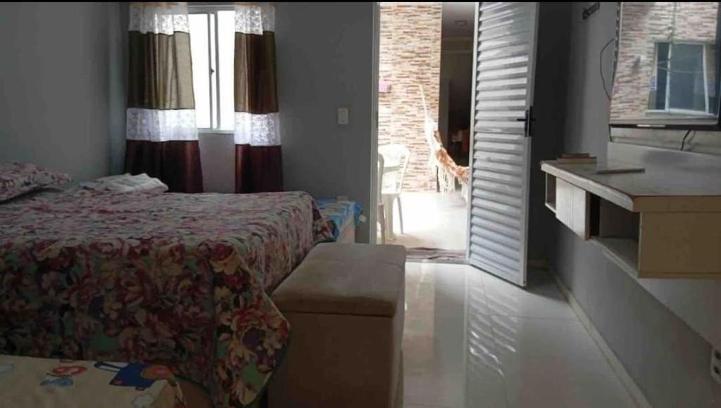 a bedroom with a bed and a bathroom with a window at Casa da Lu - Aconchego Baiano in Salvador